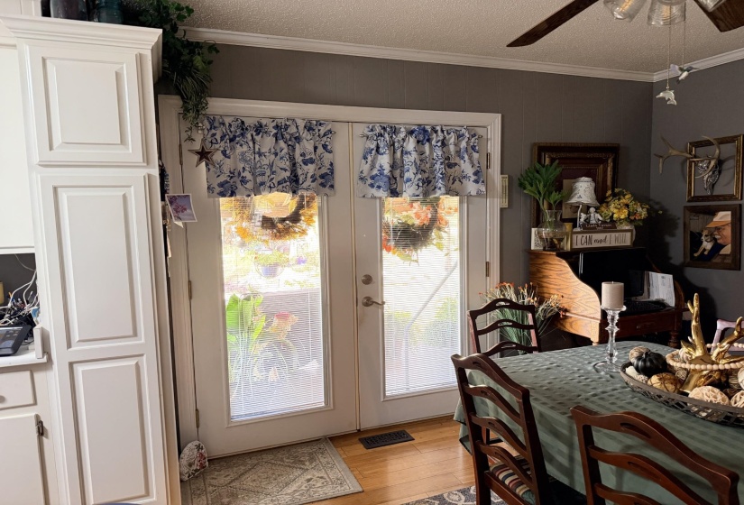 Dining area with french doors, light wood-type flooring, a textured ceiling, ceiling fan, and ornamental molding