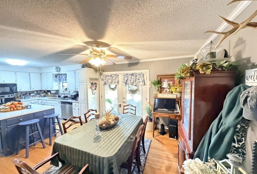 Dining area with light wood finished floors, crown molding, a ceiling fan, and a textured ceiling