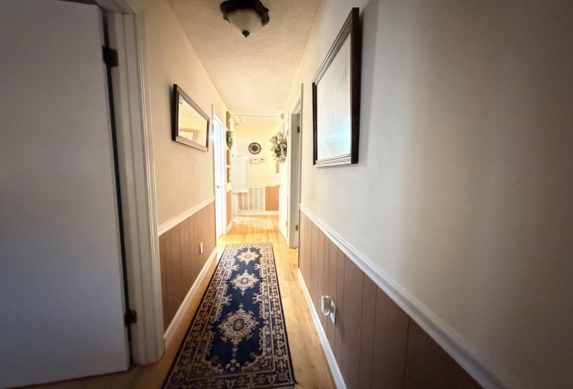 Hall with wainscoting, light wood-type flooring, and a textured ceiling