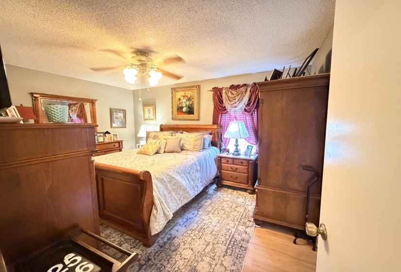 Bedroom featuring a textured ceiling, light wood finished floors, and ceiling fan