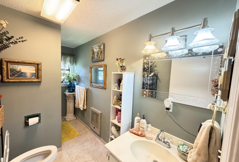 Bathroom featuring vanity, a textured ceiling, and heating unit