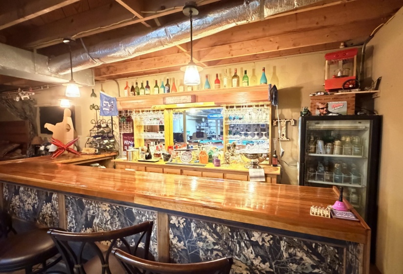 Indoor bar featuring butcher block countertops and decorative light fixtures