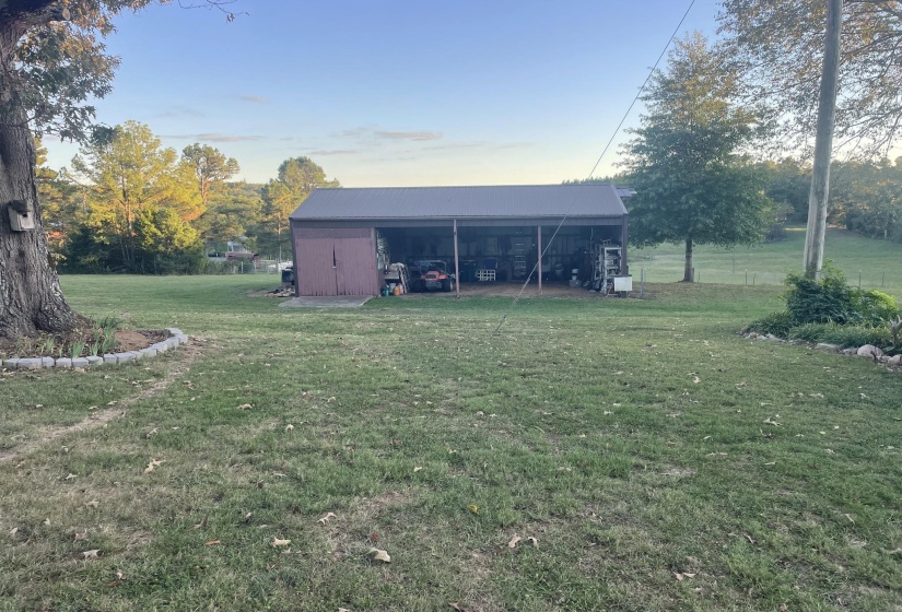 View of green lawn with a pole building, an outbuilding, and a carport