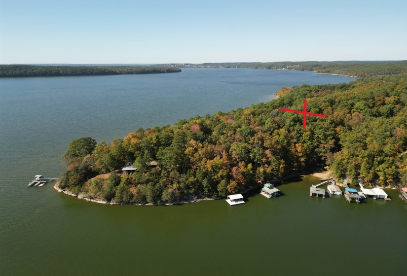 View of property location featuring a nearby body of water and a heavily wooded area