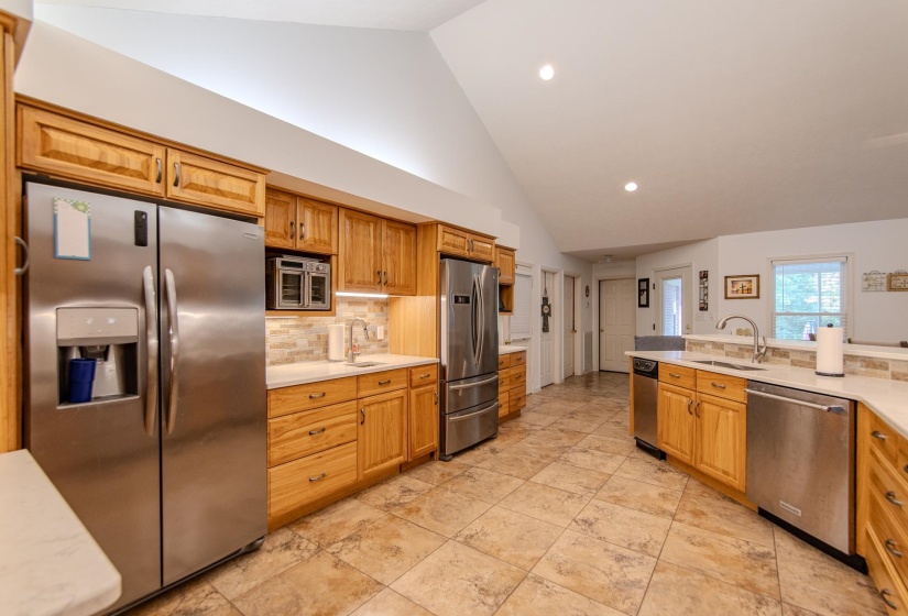 Kitchen with stainless steel appliances, tasteful backsplash, recessed lighting, high vaulted ceiling, and brown cabinetry