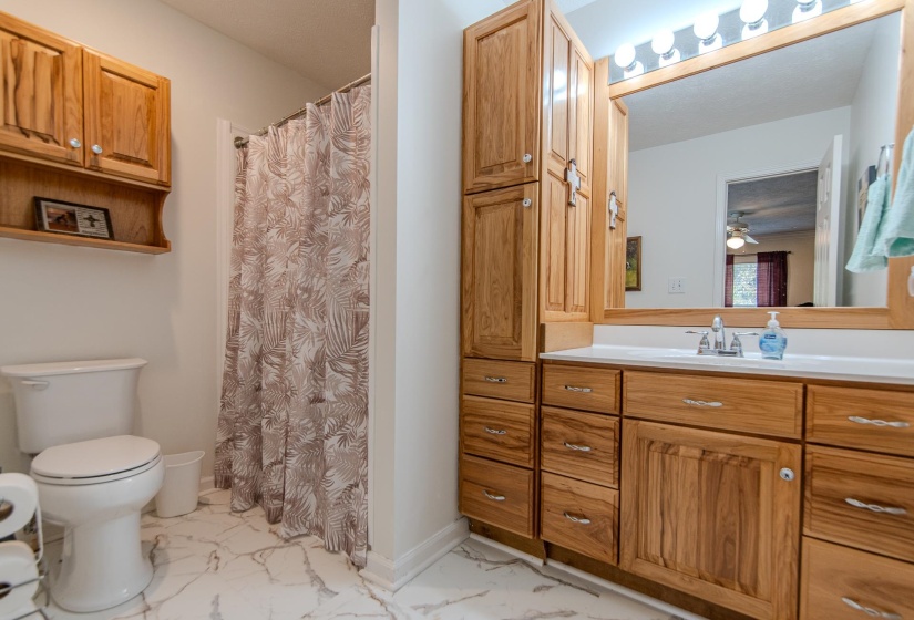 Full bathroom featuring vanity, a shower stall, light marble finish floors, and a ceiling fan