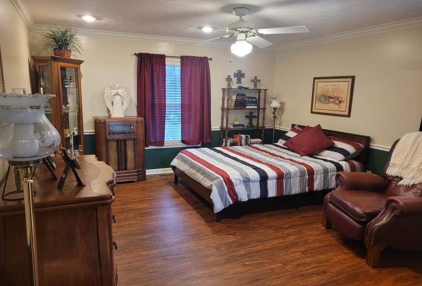 Bedroom featuring crown molding, dark wood-type flooring, and ceiling fan