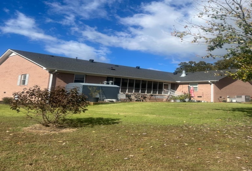Rear view of house featuring brick siding, a lawn, and a wooden deck