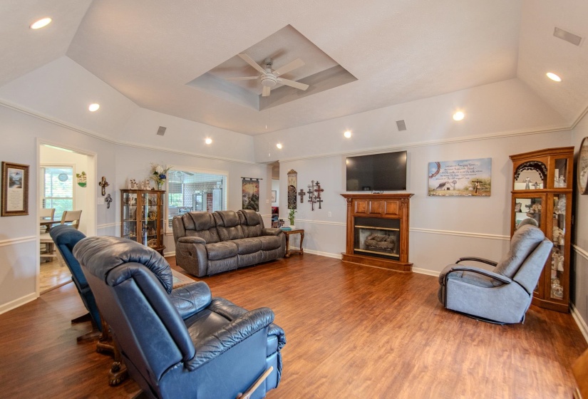 Living area featuring a raised ceiling, recessed lighting, wood finished floors, and ceiling fan