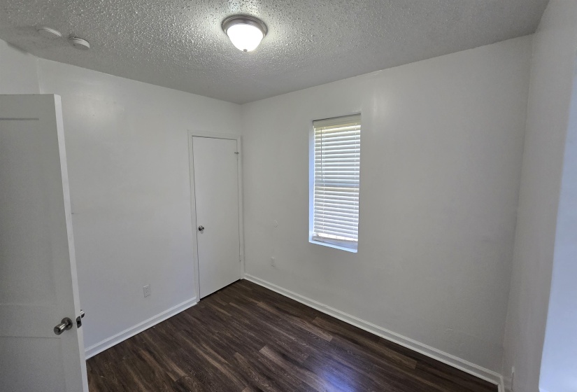 Unfurnished room featuring dark wood-style floors and a textured ceiling