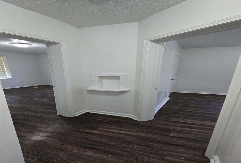 Hallway with a textured ceiling and dark wood-style floors