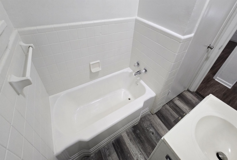 Bathroom featuring vanity, a bath, and wood finished floors