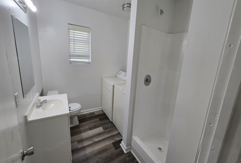 Full bath with vanity, a stall shower, dark wood finished floors, a textured ceiling, and independent washer and dryer