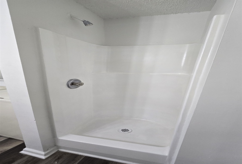 Bathroom featuring a textured ceiling, dark wood finished floors, and a stall shower