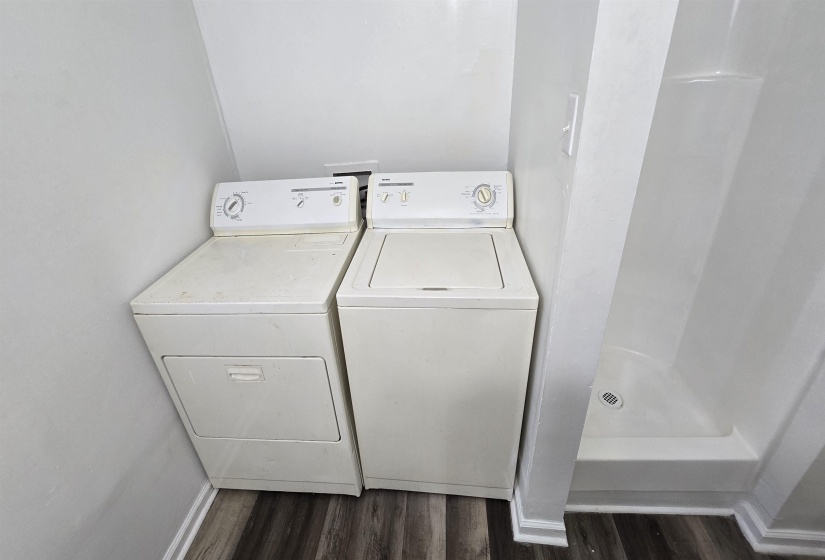 Laundry room with dark wood-style flooring and washing machine and clothes dryer