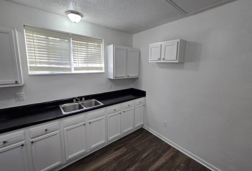 Kitchen featuring dark countertops, white cabinetry, dark wood-style floors, and a textured ceiling