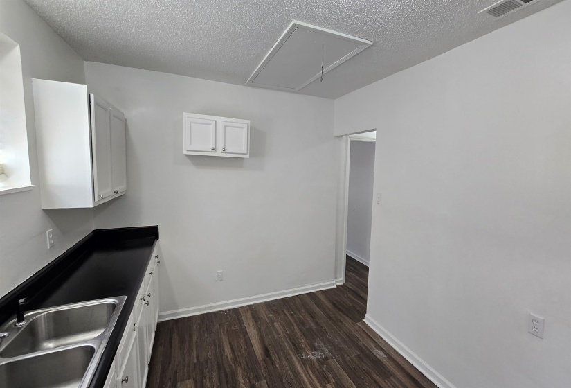 Kitchen with white cabinets, dark wood-type flooring, and a textured ceiling