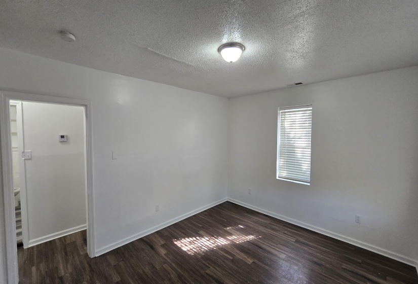 Empty room featuring a textured ceiling, dark wood-style flooring, and a smoke detector