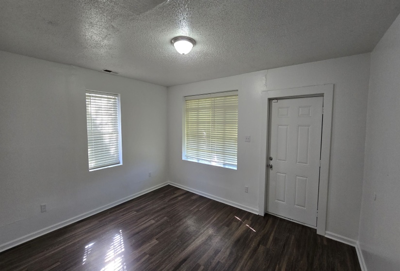 Empty room featuring a textured ceiling and dark wood-style floors