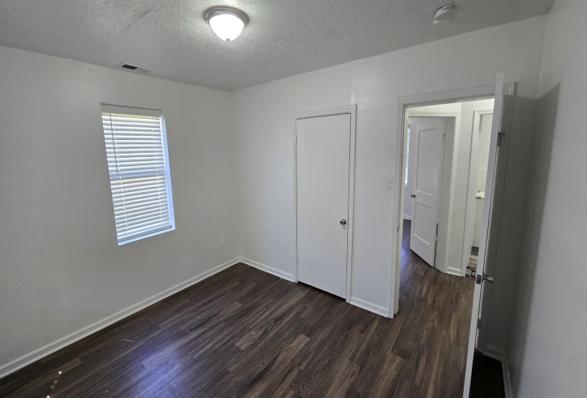Unfurnished bedroom with a textured ceiling, dark wood finished floors, and a closet
