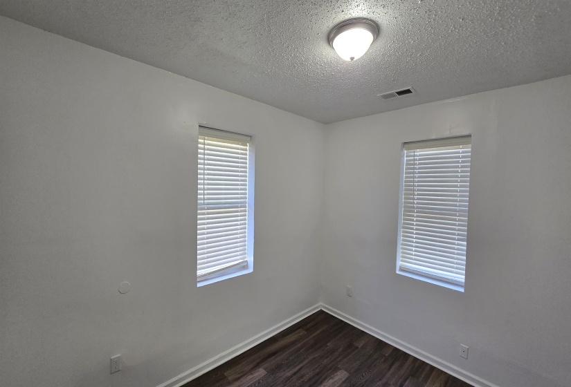 Unfurnished room featuring dark wood-type flooring and a textured ceiling
