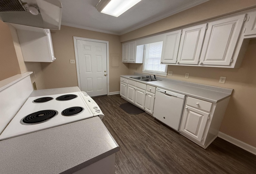 Kitchen featuring white cabinets, extractor fan, dark wood-type flooring, white appliances, and crown molding