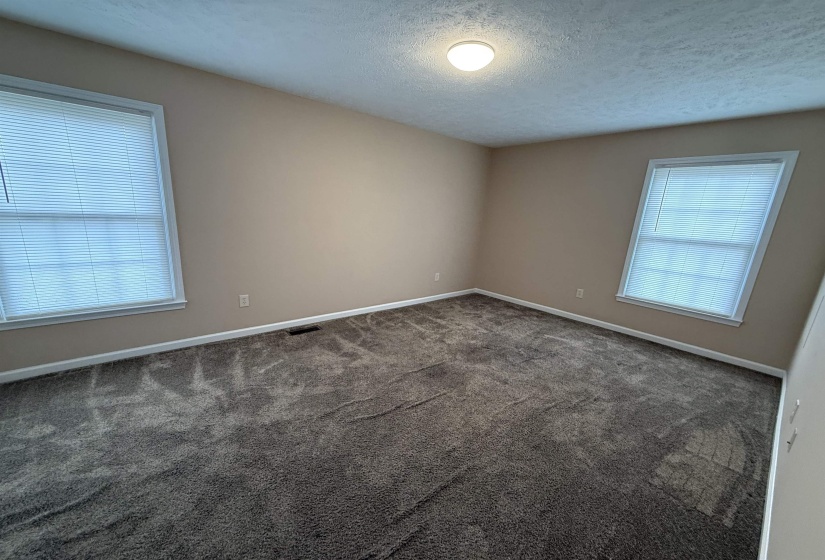 Spare room featuring a textured ceiling and dark colored carpet