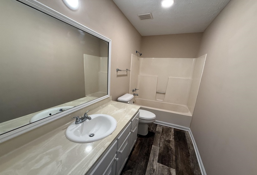 Full bath with dark wood finished floors, vanity, shower / washtub combination, and a textured ceiling