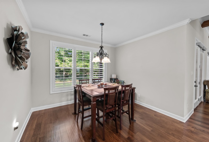 Dining room featuring dark wood-type flooring, ornamental molding, and a chandelier