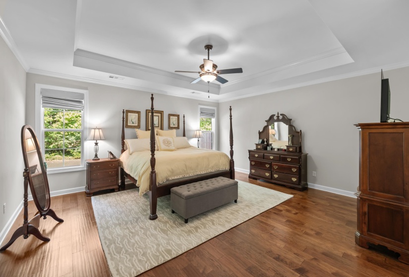 Bedroom featuring a tray ceiling, wood finished floors, crown molding, and a ceiling fan