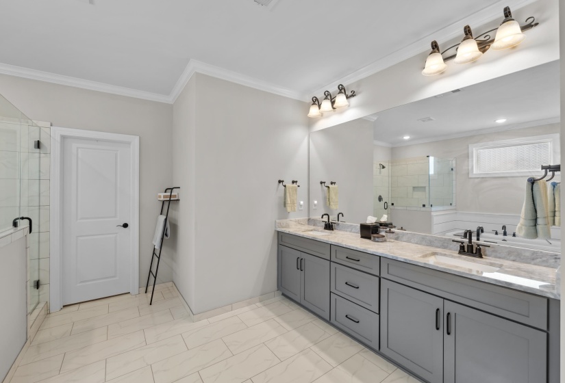 Full bathroom with double vanity, a stall shower, crown molding, and marble look tile flooring