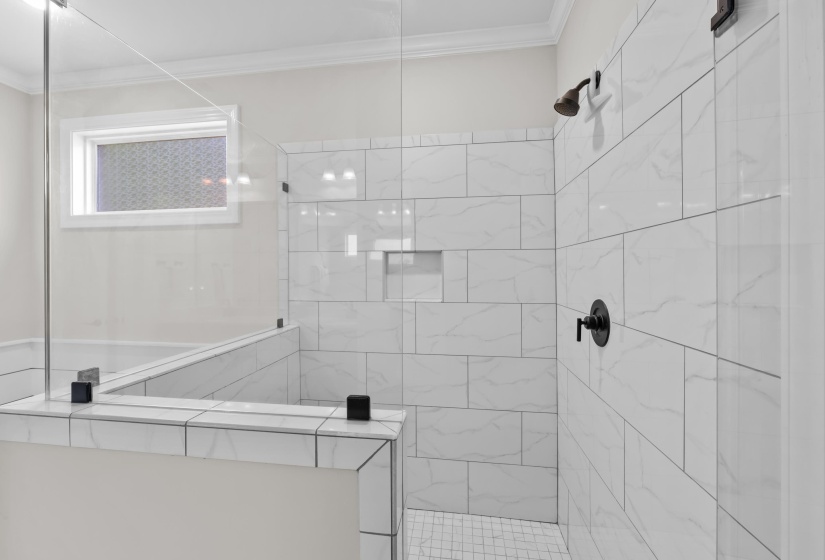 Bathroom featuring a tile shower and crown molding