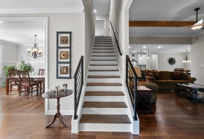 Stairway with a chandelier, wood finished floors, a ceiling fan, beamed ceiling, and crown molding
