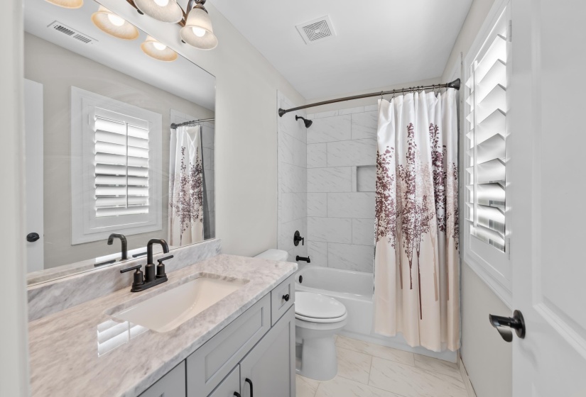 Full bath with vanity, marble look tiles, and shower / bath combination with curtain