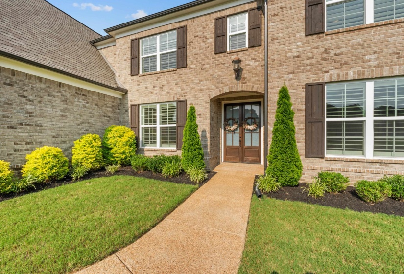 Property entrance featuring french doors, a lawn, and brick siding