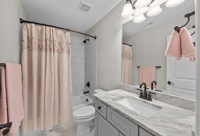 Full bath with marble finish flooring, vanity, and shower / tub combo with curtain
