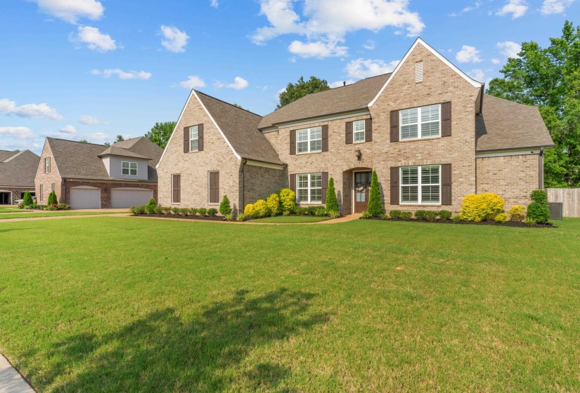 View of front facade with brick siding, a front yard, and a garage