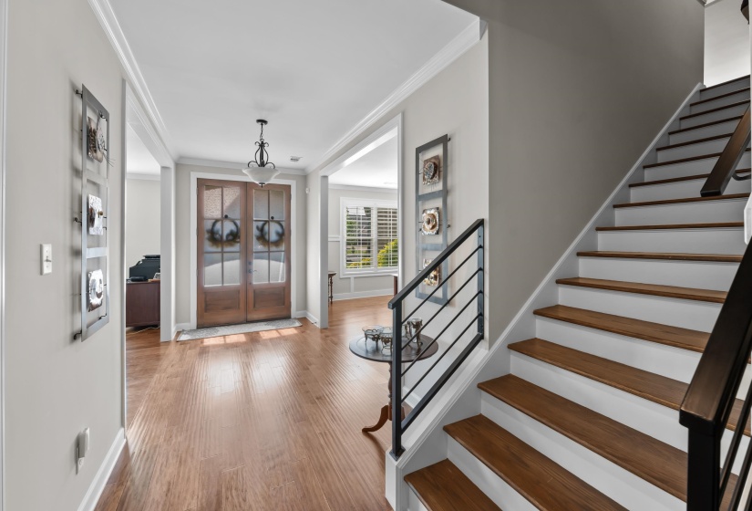 Foyer entrance with crown molding, stairs, french doors, and light wood-type flooring