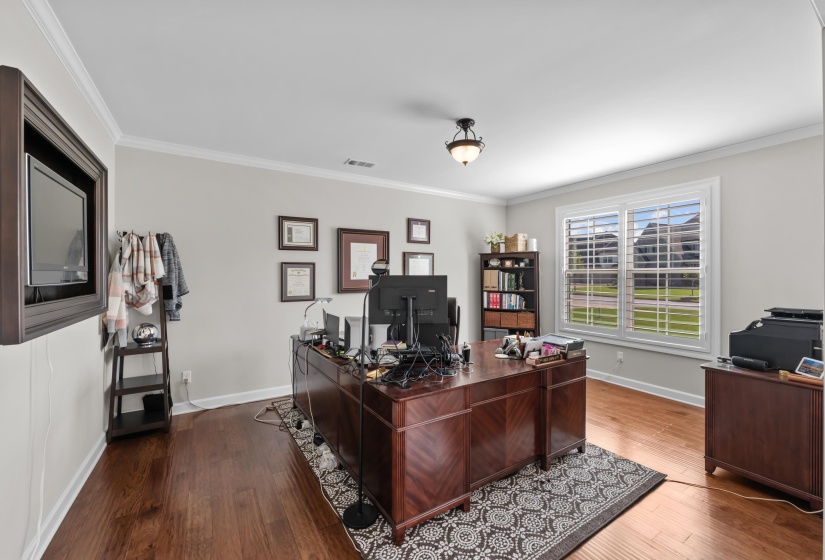 Office space with dark wood-type flooring and crown molding