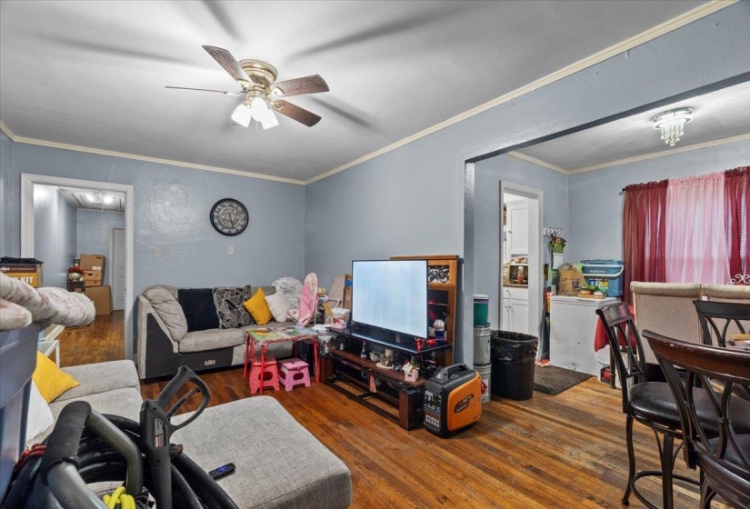Living room featuring dark wood-style flooring, ornamental molding, ceiling fan, and a textured wall