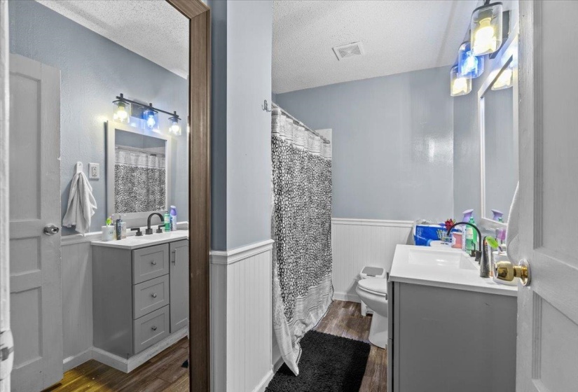 Bathroom featuring vanity, wainscoting, dark wood finished floors, a shower with shower curtain, and a textured ceiling