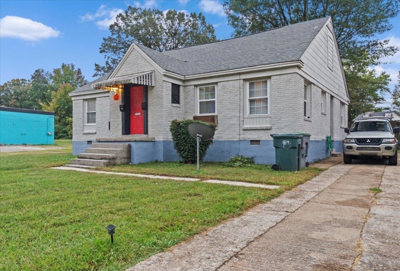 View of front of property with a front yard, brick siding, and roof with shingles