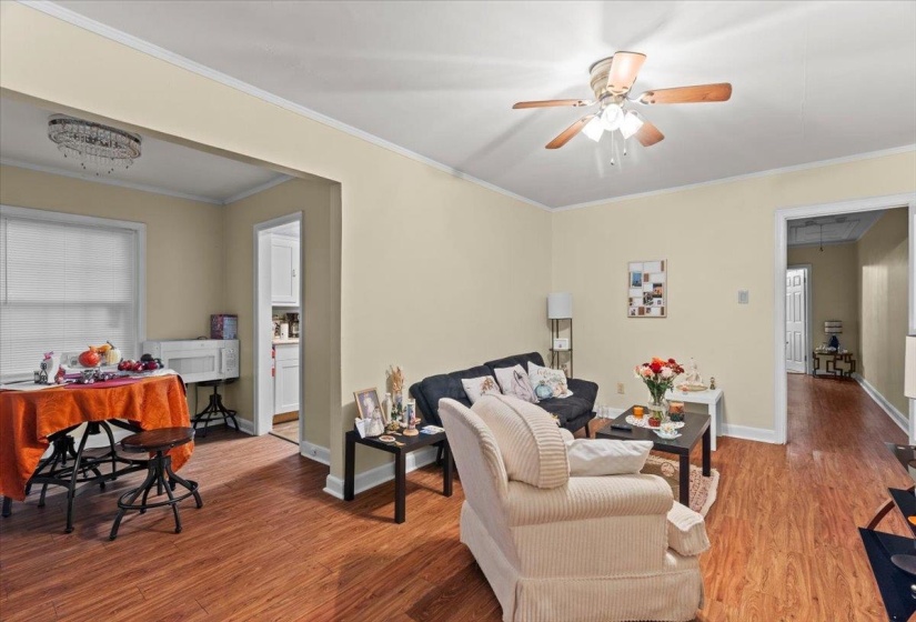 Living room featuring wood finished floors, crown molding, attic access, and ceiling fan