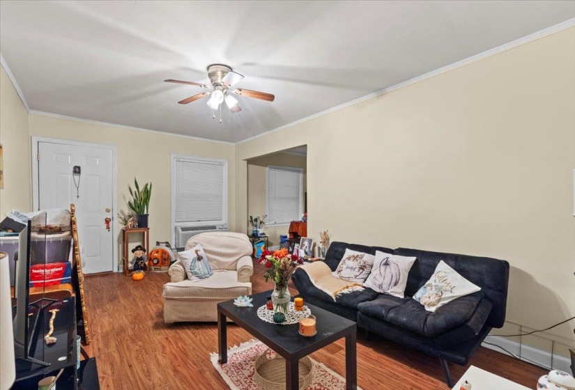 Living room with wood finished floors, ornamental molding, and ceiling fan
