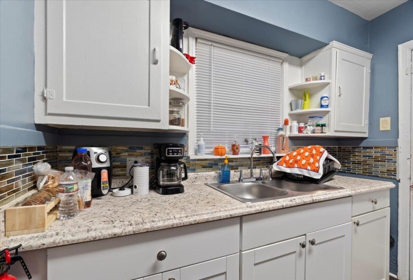Kitchen with open shelves, white cabinets, and tasteful backsplash
