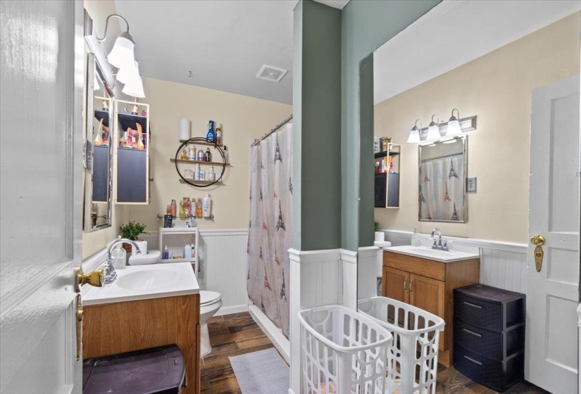 Bathroom featuring vanity, a shower stall, dark wood-type flooring, and wainscoting