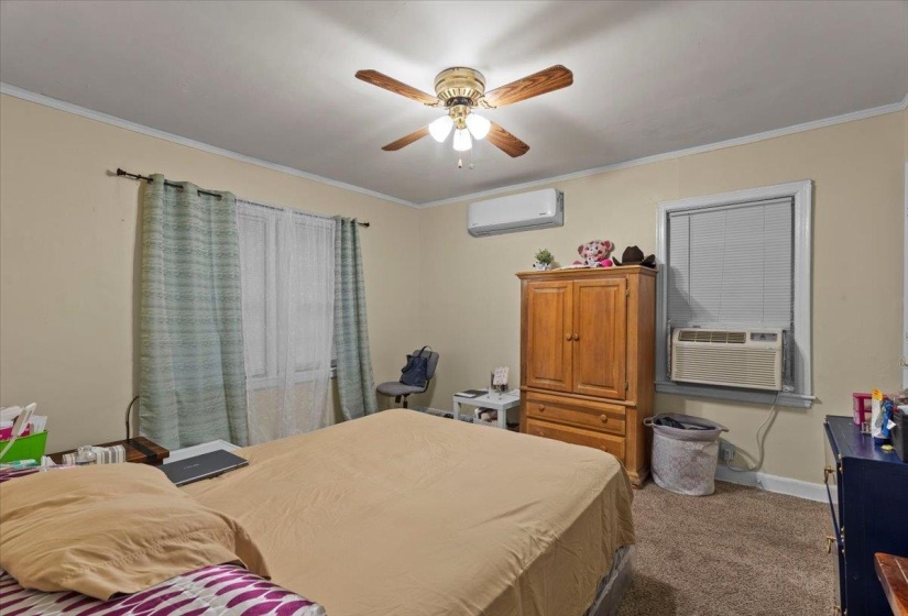 Carpeted bedroom with ornamental molding, a ceiling fan, and cooling unit