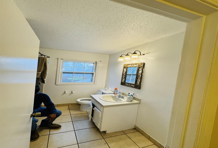 Bathroom with toilet, a textured ceiling, vanity, and tile patterned flooring