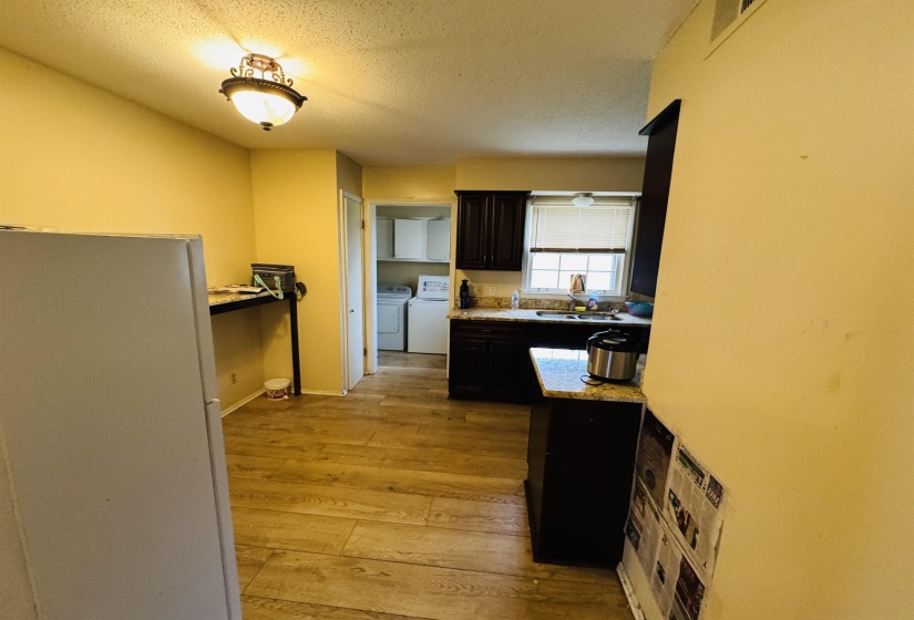 Kitchen featuring light wood-style flooring, light countertops, a textured ceiling, washer and clothes dryer, and a sink
