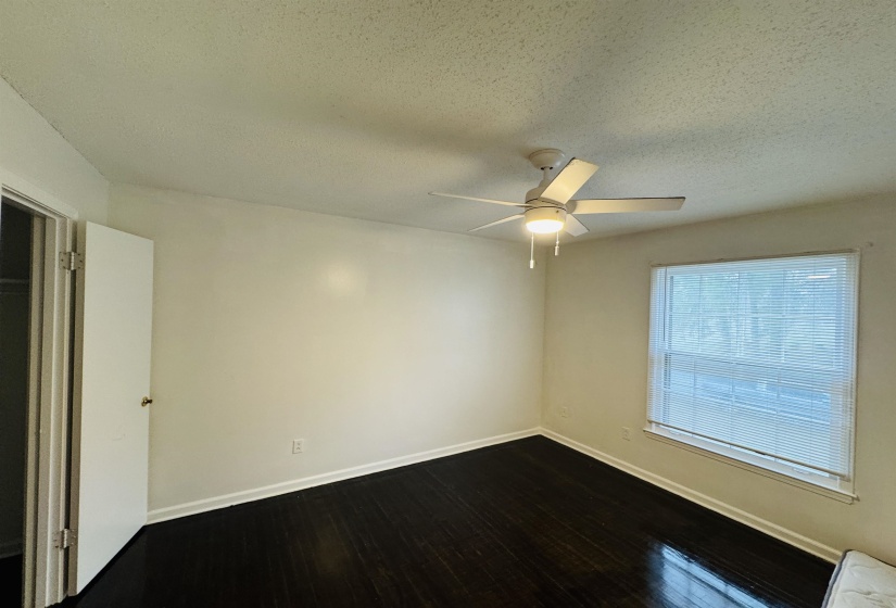 Unfurnished room with baseboards, a ceiling fan, and dark wood-style floors
